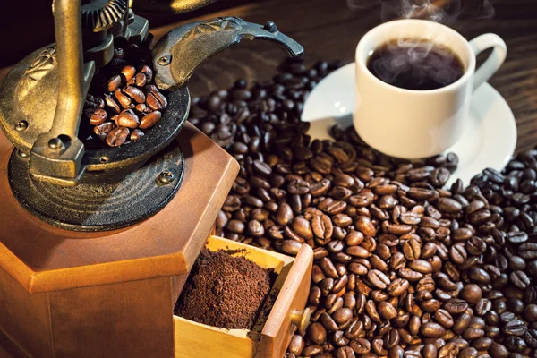 Old coffee mill and cup on wooden background