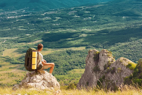 Backpacker siedzi na skale i patrząc na dolinie — Zdjęcie stockowe