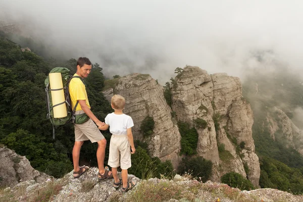 Backpacker met zoontje in de mistige bergen. — Stockfoto