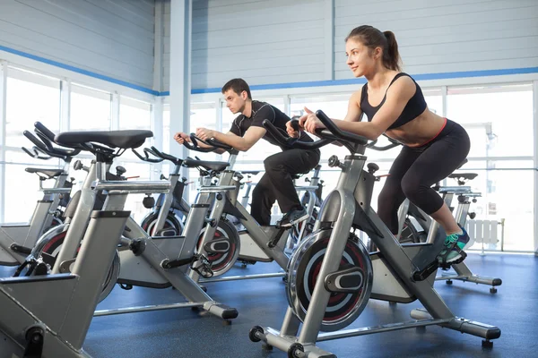 Bicicletas estáticas para hombres y mujeres en el gimnasio —  Fotos de Stock