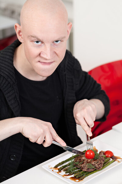 Young man sitting at sushi bar, smiling