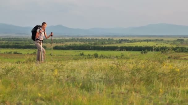 Молода жінка з рюкзаком ходить на природі під час літнього сонячного дня — стокове відео