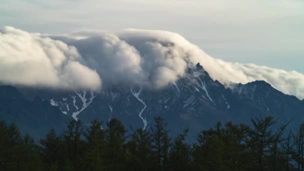 Nube nebbia sulla catena montuosa e il lasso di tempo foresta. Montagna innevata picco e nebbia su di esso. All'aperto — Video Stock