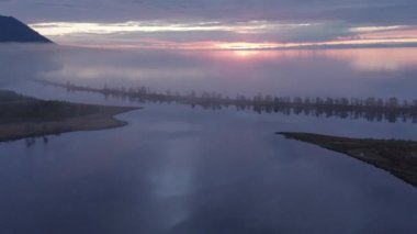 Gün batımında göl, hava manzarası. Sis içinde Baykal şafağı. Dağ ve sahil kum şeridi