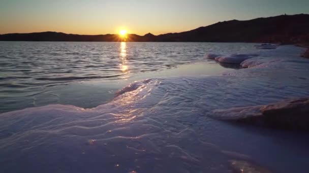 Озеро Байкал со льдом на берегу в лучах заката. Замерзающая вода в декабре. Чистое небо — стоковое видео