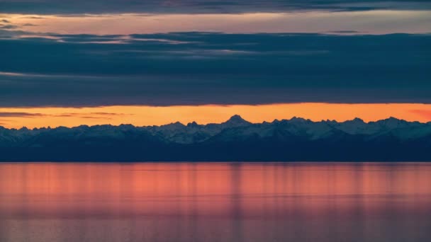 Caduta dell'alba del lago e delle montagne innevate. Nuvole che si muovono sul mare rosa calmo, paesaggio nuvoloso — Video Stock