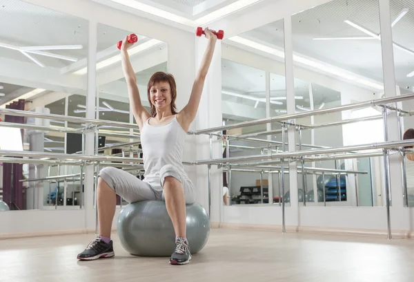 用球和 barbelll 在健身房里嬉戏女人 — 图库照片