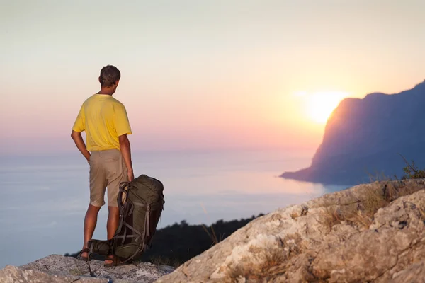 Man met rugzak en op zoek bij zonsopgang — Stockfoto