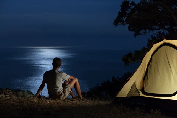 Homem perto da tenda iluminada à noite — Fotografia de Stock