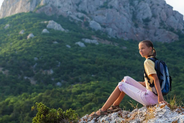 Jeune femme avec sac à dos assis sur un rocher — Photo