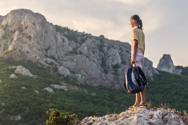 Jeune femme avec sac à dos se tient sur un rocher — Photo