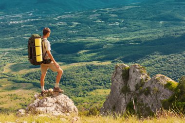 Backpacker yüksek bir kaya ve büyük yeşil valley adlı arıyorsunuz
