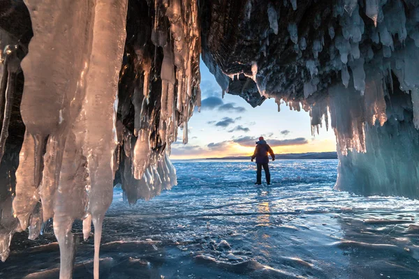 Wandelaar op het ijs-grot en over zonsopgang. — Stockfoto