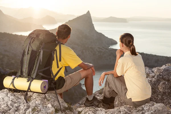 Twee wandelaars lopen een berg en kijken naar de zonsopgang boven t — Stockfoto