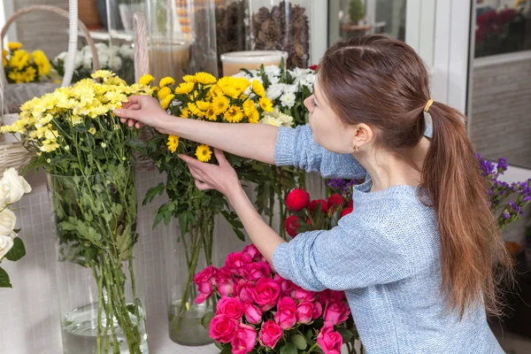 Mujer cuidando flores en la tienda — Foto de Stock