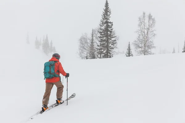 Homem esquiando encosta nevada — Fotografia de Stock