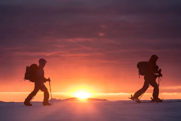 Deux skieurs marchent dans les montagnes contre le coucher du soleil — Photo