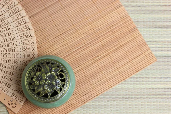 Chinese incense burner on the bamboo mat background.