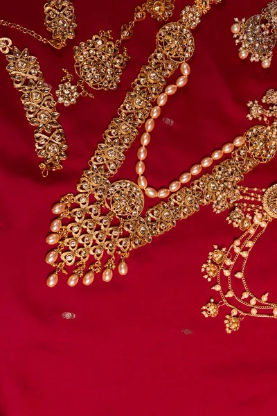 Indian traditional gold Indian wedding women\'s jewelry on red sari background. Close-up. Still-life.