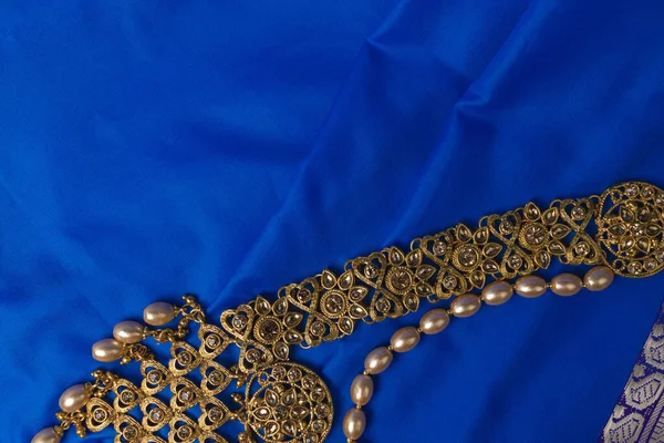 Indian traditional gold Indian wedding women\'s jewelry on blue saree background. Close-up. Still-life.