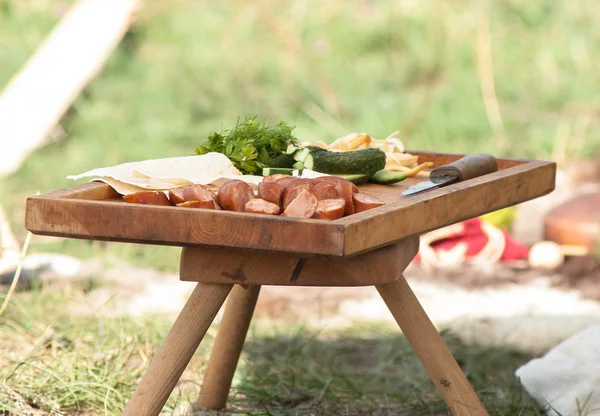 Picnic table, meat, knife, green summer holiday — Stock Photo, Image