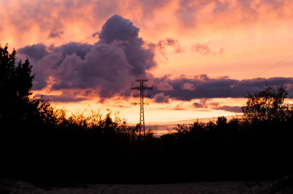 Cojinete líneas eléctricas en una puesta de sol — Foto de Stock