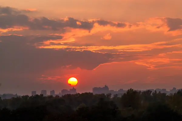 The sun at sunset with clouds over the city — Stock Photo, Image