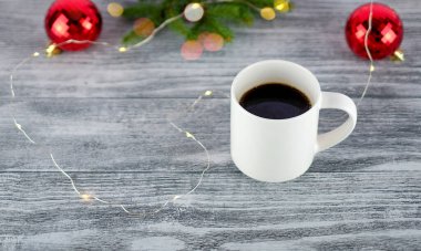 Beyaz bir fincan kahve ve ahşap arka planda Noel süsü. Yeni yıl sabahı