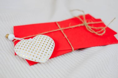 Kırmızı zarfların üzerinde beyaz kalp oyuncağı beyaz örgü arka planda tatiller için. Seçici odak