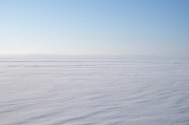 Kış manzarası, karla kaplı deniz ve açık havada mavi gökyüzü.