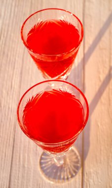 Kırmızı likör ve güneş ışığı efektli iki bardak. Soyut arkaplan, yakın plan, seçici odak