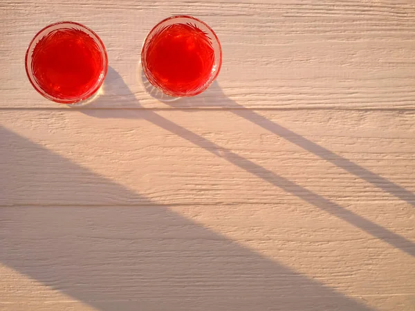Paar Gläser mit Rotwein auf dem hölzernen Hintergrund mit Sonnenlicht. Abstrakter Hintergrund. Ansicht von oben. Kopierraum — Stockfoto