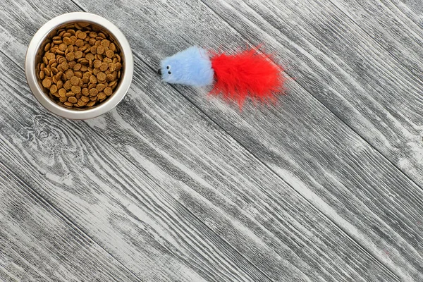 Food for pet in bowl and mouse toys on wooden background top view, copy space — Stock Photo, Image