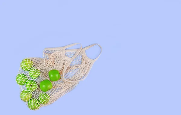 Katoen mesh bag met groene appels op blauwe achtergrond, milieuvriendelijk concept, bovenaanzicht, kopieerruimte Stockfoto