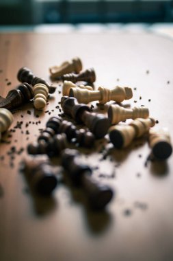 Satranç taşları ahşap bir masaya saçılmış.