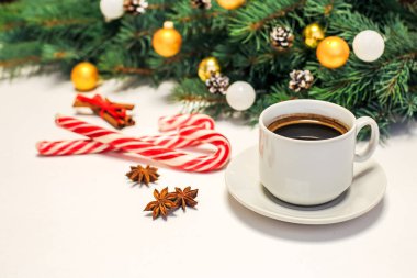 Masada bir fincan kahve, süslemeler, köknar dalları, şeker ve tarçın olan bir Noel düzeni. Yeni Yıl