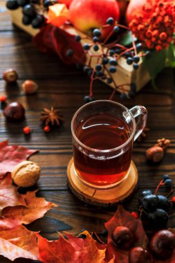 Bir fincan çay, sonbahar yaprakları, meyveler ve fındıklı sonbahar kompozisyonu