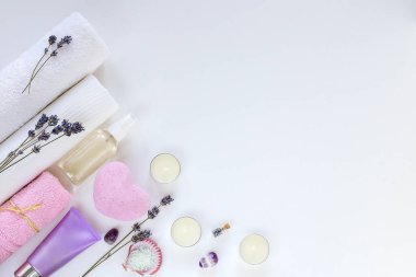 Beyaz arka planda kaplıca ve havlular, kuru lavanta, aroma yağları ve deniz tuzu.