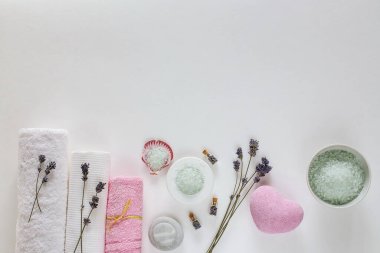 Beyaz arka planda kaplıca ve havlular, kuru lavanta, aroma yağları ve deniz tuzu.