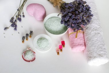Beyaz arka planda kaplıca ve havlular, kuru lavanta, aroma yağları ve deniz tuzu.