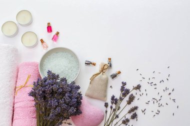 Beyaz arka planda kaplıca ve havlular, kuru lavanta, aroma yağları ve deniz tuzu.