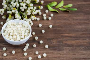 Ökseotu meyvesi ve ağaç bir yüzey üzerinde ebediyen yeşil beyaz ökseotu dalları olan bir kap.