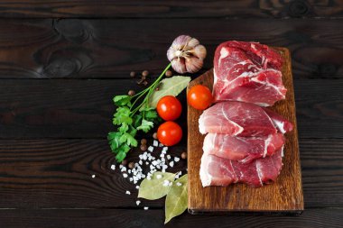 Çiğ et parçaları. Tahta üzerinde baharat ve baharatlarla dilimlenmiş taze et. Boşluğun kopyası