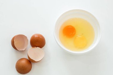 Çiğ tavuk yumurtaları ve kırık kabuklar. Beyaz tabakta yumurta sarısı.