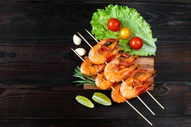 Ahşap tezgahta sebze ve otlarla ızgara karides. Restoran menüsü, Akdeniz mutfağı. Şişte ızgara karides.