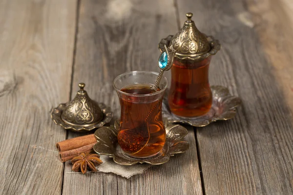 Turkish tea cups and some cinnamon sticks on a wooden background