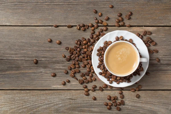 Por la mañana taza de café fresco con granos de café en una mesa de madera —  Fotos de Stock