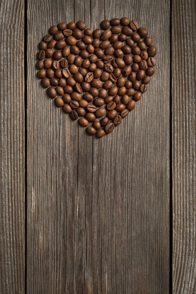 Grains de café en forme de coeur sur fond en bois — Photo