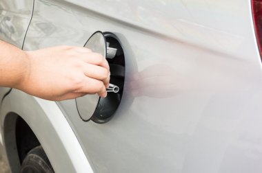 Bir adam operning gümüş bir otomobilin yakıt tankı kapağı