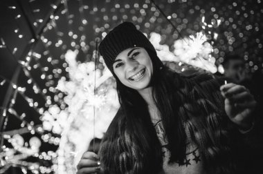 Noel panayırının yanında elinde pırıltılarla duran güzel genç bayan. 